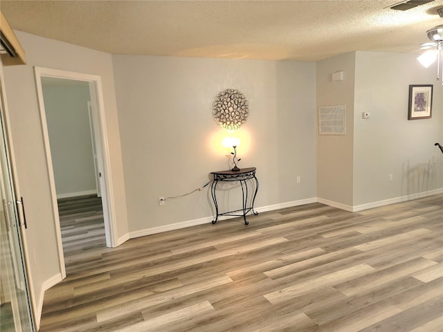 spare room featuring hardwood / wood-style flooring, ceiling fan, and a textured ceiling