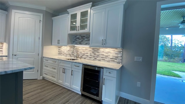 kitchen with light stone countertops, sink, white cabinets, and beverage cooler