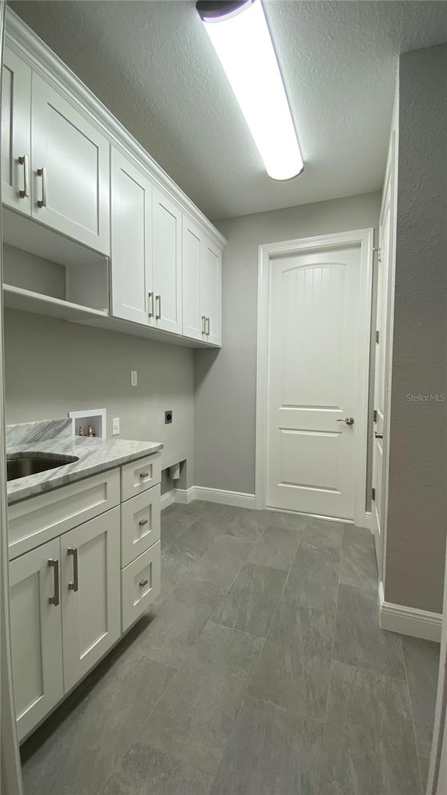 washroom with hookup for an electric dryer, hookup for a washing machine, cabinets, tile patterned floors, and a textured ceiling