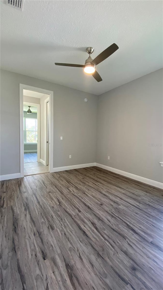 unfurnished room featuring ceiling fan, dark hardwood / wood-style flooring, and a textured ceiling