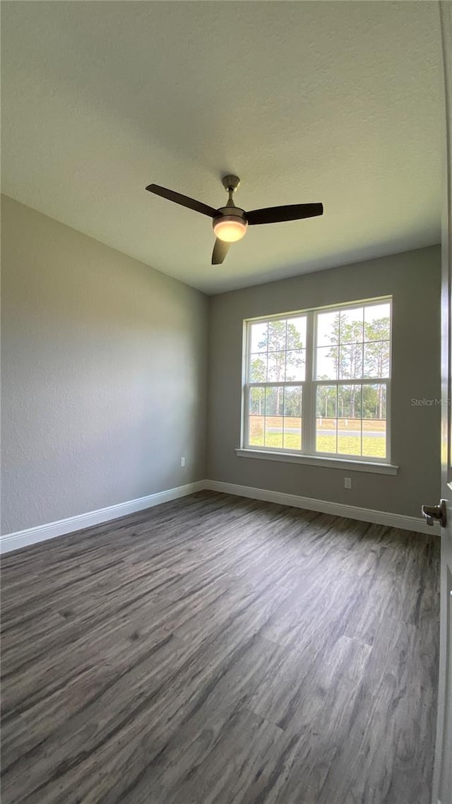 unfurnished room with dark hardwood / wood-style flooring and ceiling fan