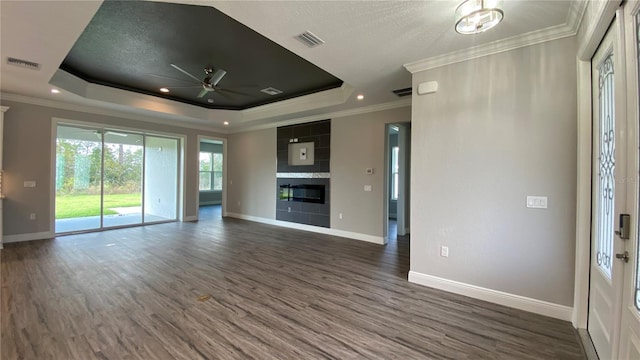 unfurnished living room with crown molding, a raised ceiling, visible vents, dark wood-type flooring, and a tile fireplace