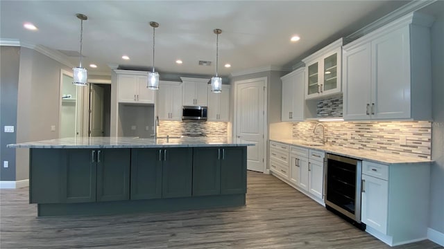 kitchen with a spacious island, wine cooler, stainless steel microwave, decorative light fixtures, and white cabinetry