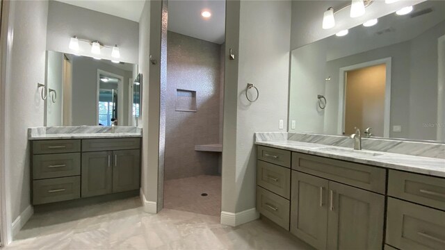 bathroom featuring a walk in shower, two vanities, a sink, and baseboards