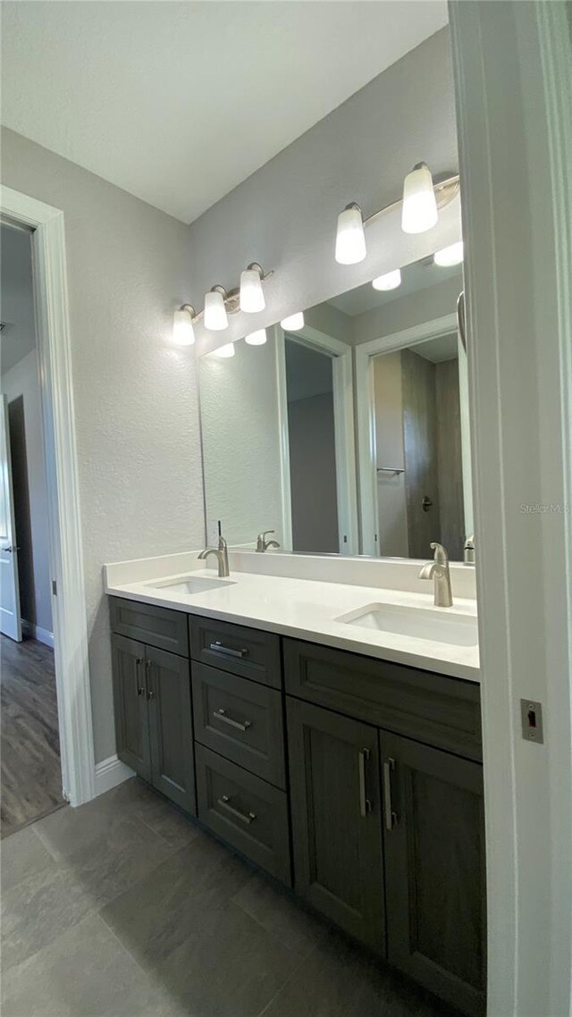 full bath with double vanity, baseboards, and a sink