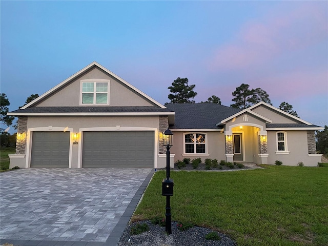 view of front of house featuring decorative driveway, an attached garage, a front lawn, and stucco siding