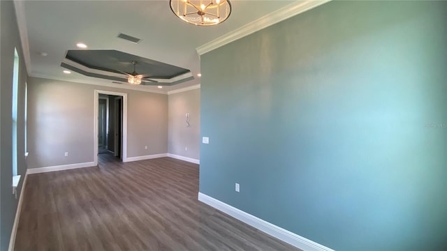 unfurnished room featuring baseboards, a raised ceiling, dark wood-style floors, crown molding, and ceiling fan with notable chandelier