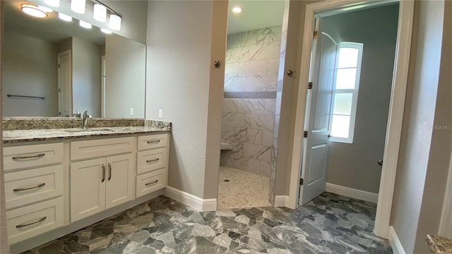 bathroom featuring a healthy amount of sunlight, marble finish floor, walk in shower, and vanity