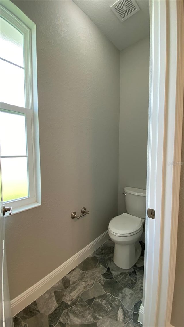 bathroom with toilet, visible vents, and baseboards