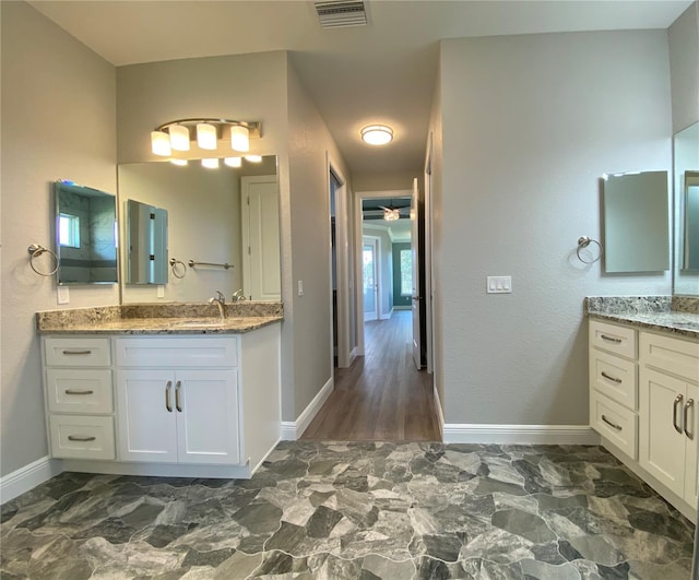 bathroom with marble finish floor, two vanities, visible vents, a sink, and baseboards