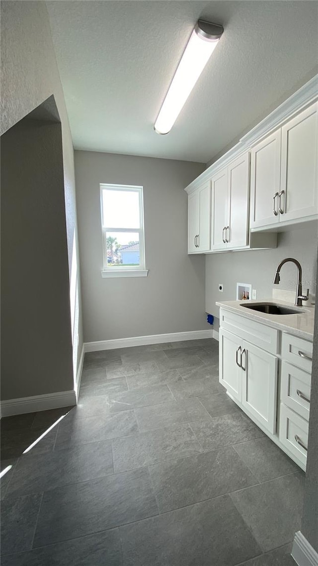 laundry room featuring hookup for a washing machine, cabinet space, a sink, electric dryer hookup, and baseboards