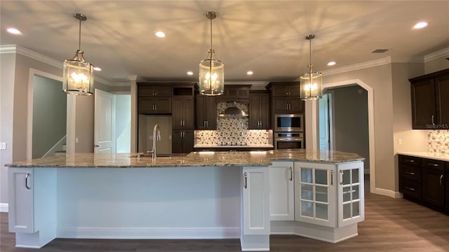 kitchen with dark brown cabinets, appliances with stainless steel finishes, a sink, and pendant lighting