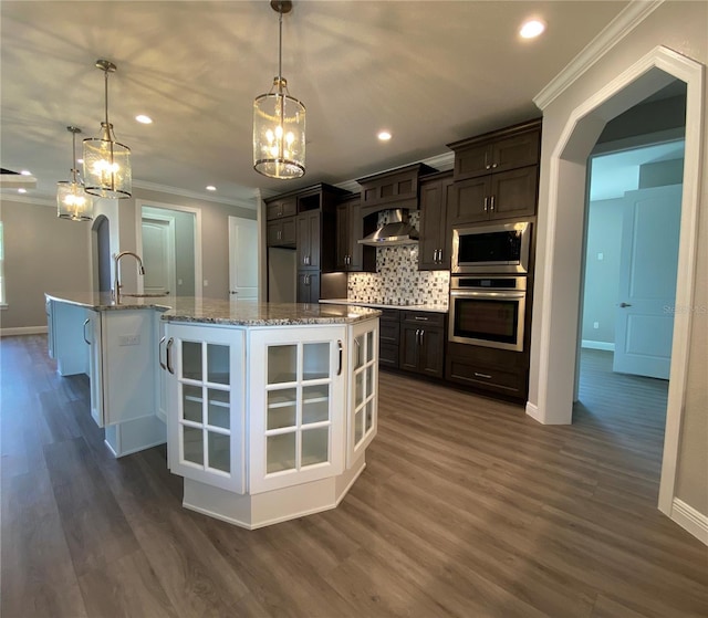 kitchen with arched walkways, stainless steel appliances, dark brown cabinets, and pendant lighting