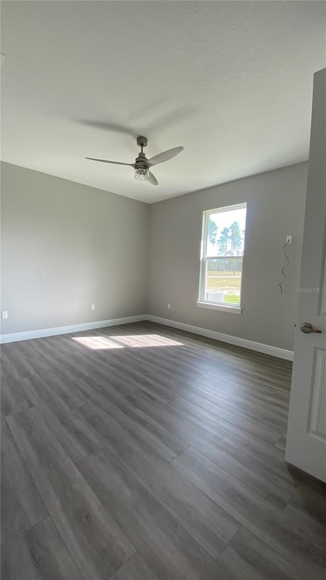 empty room with dark wood finished floors, baseboards, and ceiling fan