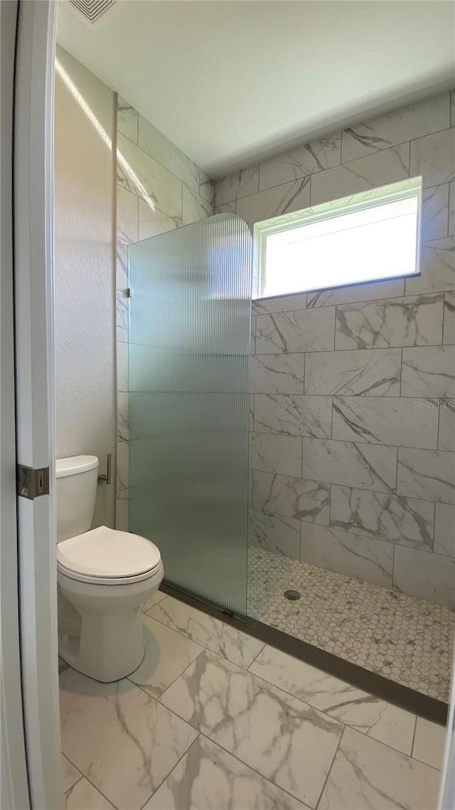 full bath featuring toilet, marble finish floor, and walk in shower