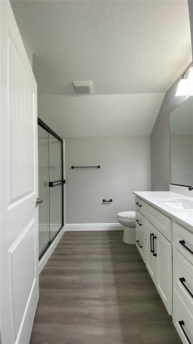 full bath with toilet, a stall shower, vanity, a textured ceiling, and wood finished floors