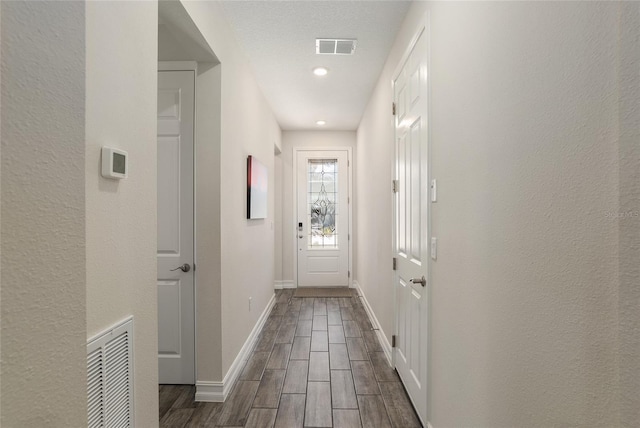 doorway to outside featuring a textured ceiling and dark hardwood / wood-style flooring