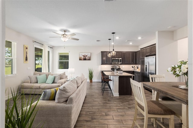 living room with dark hardwood / wood-style flooring, a textured ceiling, and ceiling fan