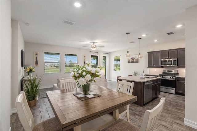 dining area with ceiling fan, sink, and light hardwood / wood-style floors