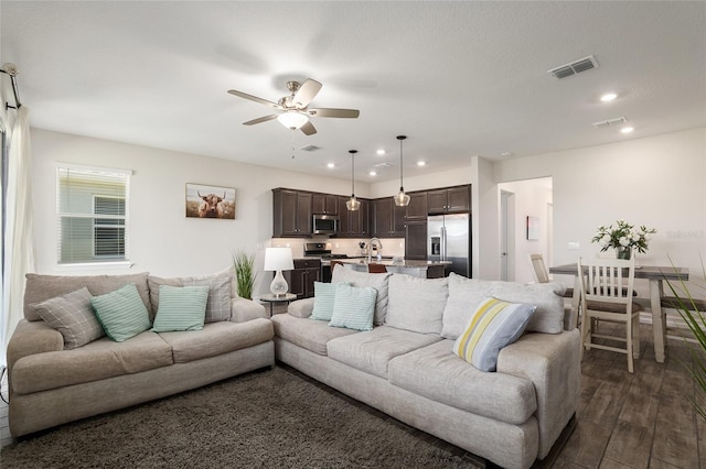 living room featuring dark hardwood / wood-style flooring, sink, and ceiling fan