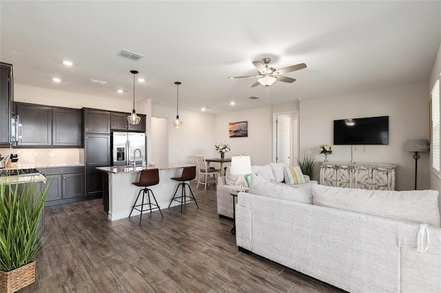 living room with dark hardwood / wood-style flooring, sink, and ceiling fan