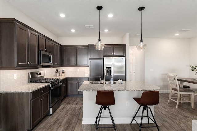 kitchen with stainless steel appliances, light stone countertops, decorative light fixtures, and dark hardwood / wood-style flooring