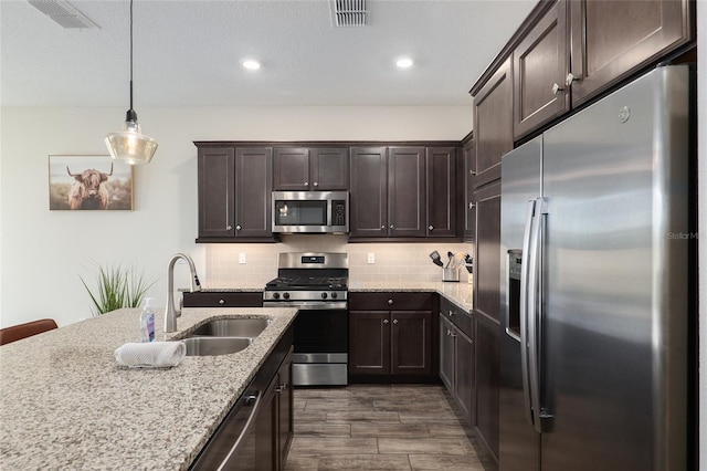 kitchen with appliances with stainless steel finishes, dark hardwood / wood-style flooring, pendant lighting, decorative backsplash, and sink