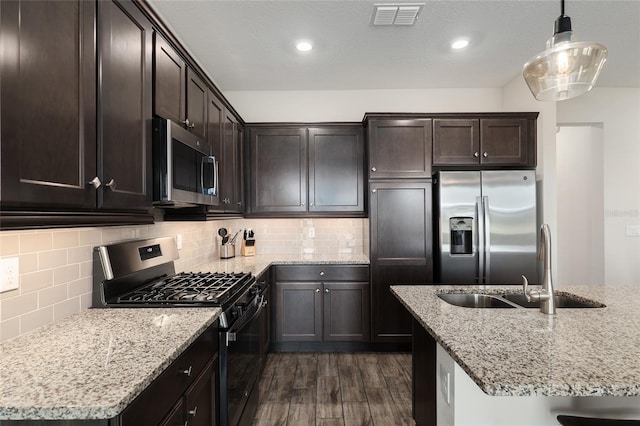 kitchen featuring stainless steel appliances, sink, tasteful backsplash, hanging light fixtures, and dark hardwood / wood-style flooring