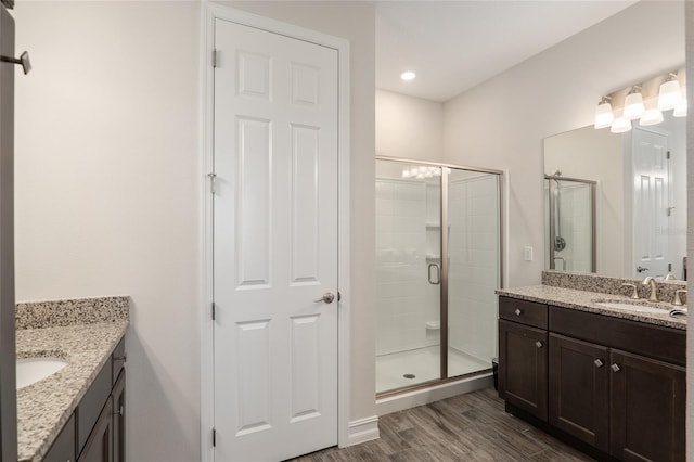 bathroom with an enclosed shower, vanity, and wood-type flooring