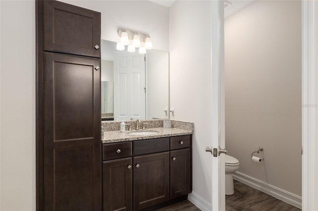 bathroom with hardwood / wood-style flooring, vanity, and toilet