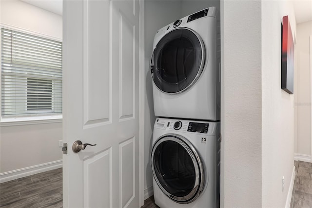 clothes washing area with stacked washer / dryer and wood-type flooring