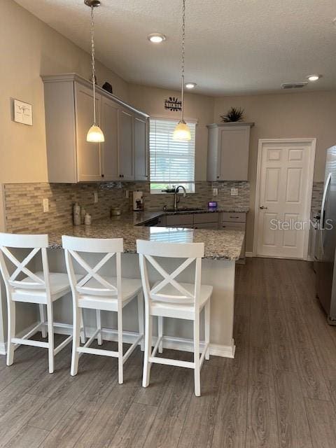 kitchen featuring gray cabinetry, hanging light fixtures, and a kitchen bar