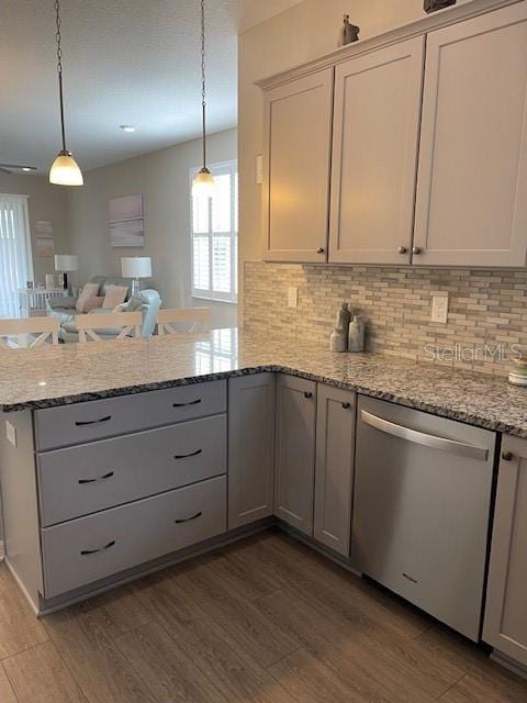 kitchen featuring light stone counters, pendant lighting, dark wood-type flooring, stainless steel dishwasher, and kitchen peninsula