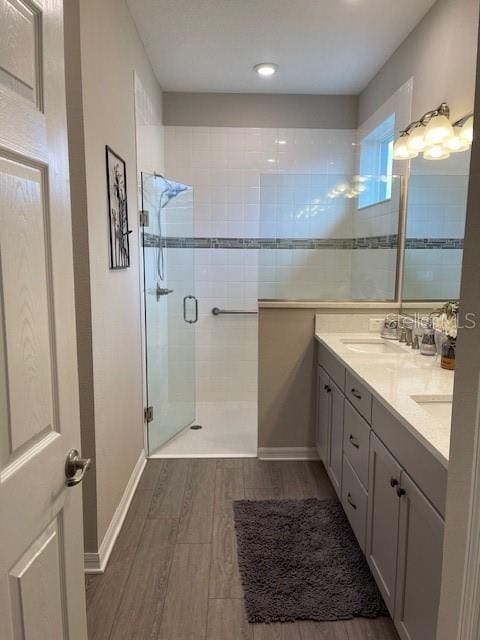 bathroom with hardwood / wood-style floors, walk in shower, and vanity