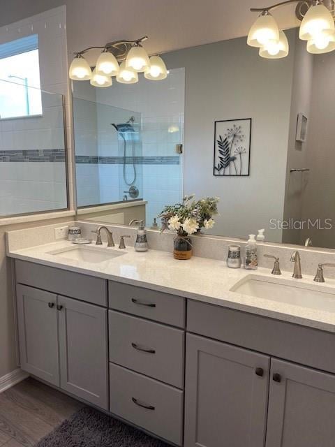 bathroom with hardwood / wood-style flooring, vanity, and tiled shower