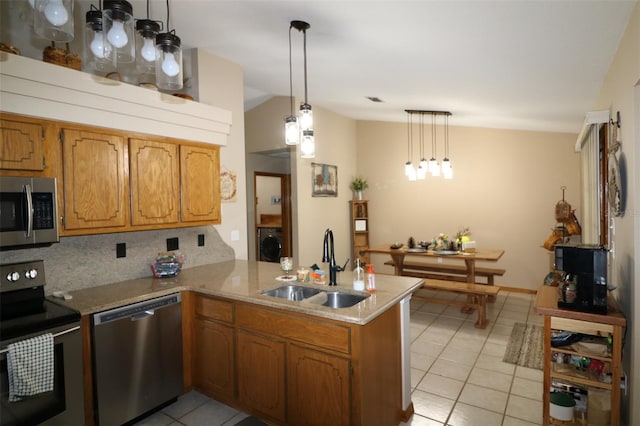 kitchen with sink, appliances with stainless steel finishes, kitchen peninsula, backsplash, and pendant lighting