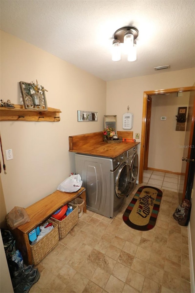 clothes washing area featuring washing machine and clothes dryer and a textured ceiling