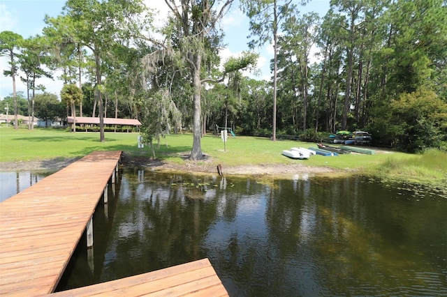 view of dock with a lawn and a water view