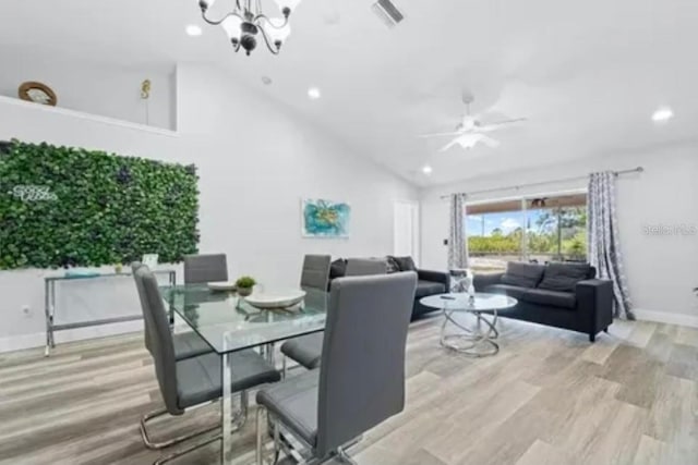 dining space featuring light hardwood / wood-style floors, ceiling fan with notable chandelier, and high vaulted ceiling