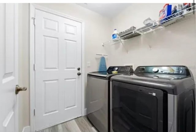 clothes washing area featuring light hardwood / wood-style floors and washer and clothes dryer