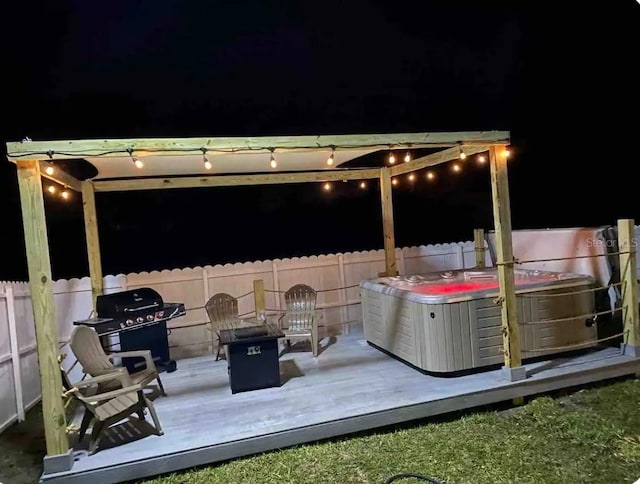 deck at twilight featuring a hot tub, a grill, an outdoor fire pit, and a patio