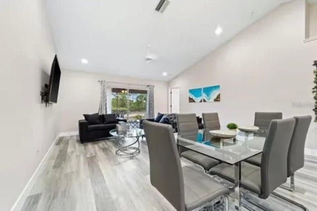 dining area featuring high vaulted ceiling and light wood-type flooring