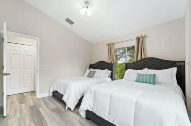 bedroom with vaulted ceiling and light hardwood / wood-style floors