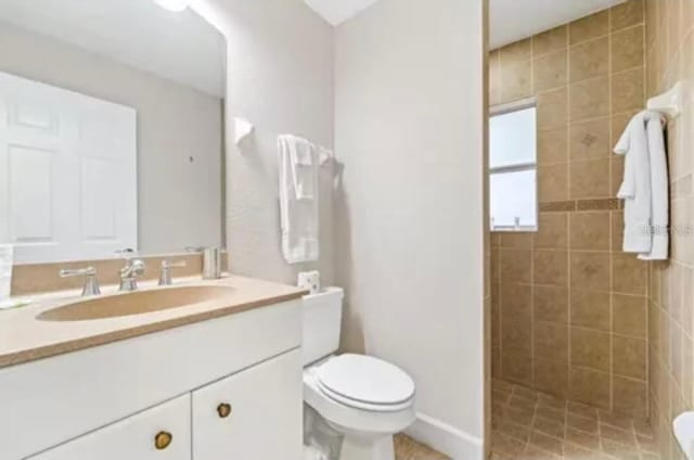 bathroom featuring toilet, vanity, and a tile shower