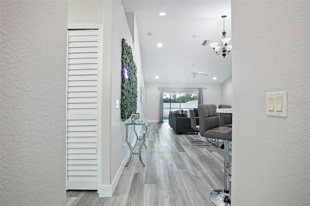 corridor featuring recessed lighting, a textured wall, visible vents, wood finished floors, and a notable chandelier