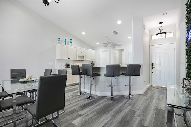 dining area with light wood-style flooring, a ceiling fan, visible vents, vaulted ceiling, and recessed lighting
