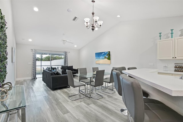 dining space featuring ceiling fan with notable chandelier, high vaulted ceiling, light wood-style flooring, visible vents, and recessed lighting