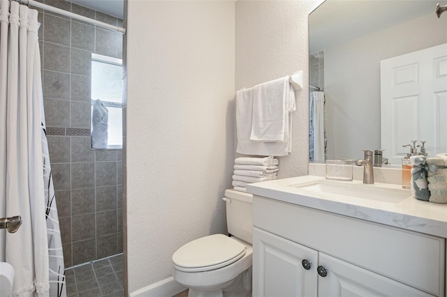 full bath with a tile shower, a textured wall, toilet, and vanity