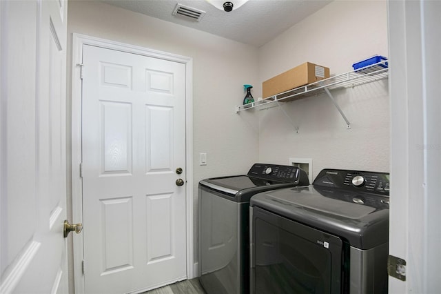 laundry room with washer and dryer, laundry area, light wood finished floors, and visible vents
