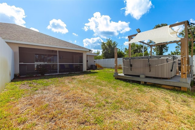 view of yard with central AC unit, a fenced backyard, a sunroom, and a hot tub